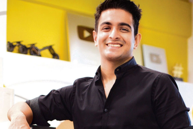 Ranveer Allahbadia smiling in a studio setup with YouTube awards in the background