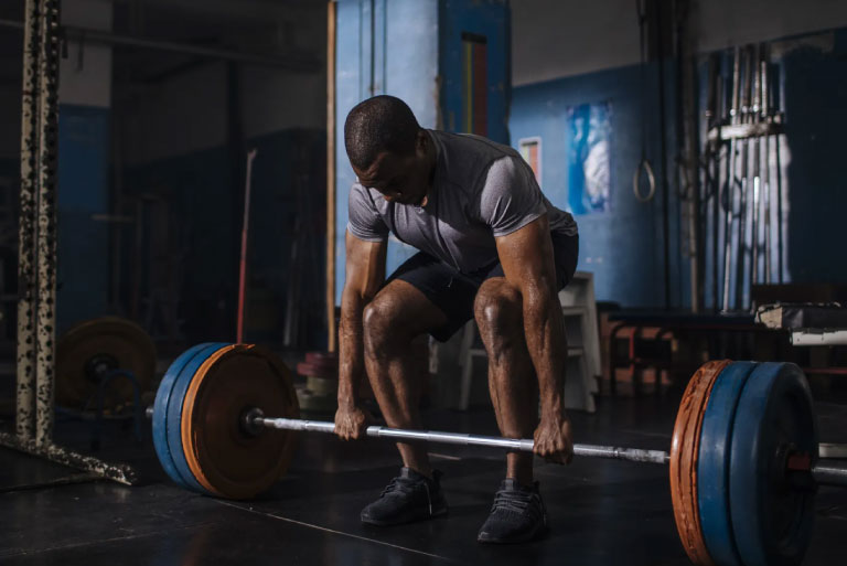 A man performing heavy powerlifting with a loaded barbell, representing strength training and weight gain to 90 kg.