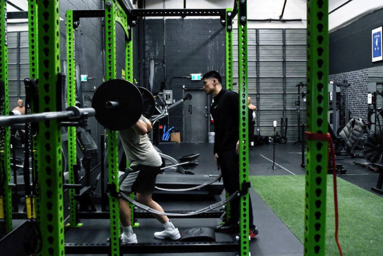 A man training with controlled form in a gym while following a structured workout plan.